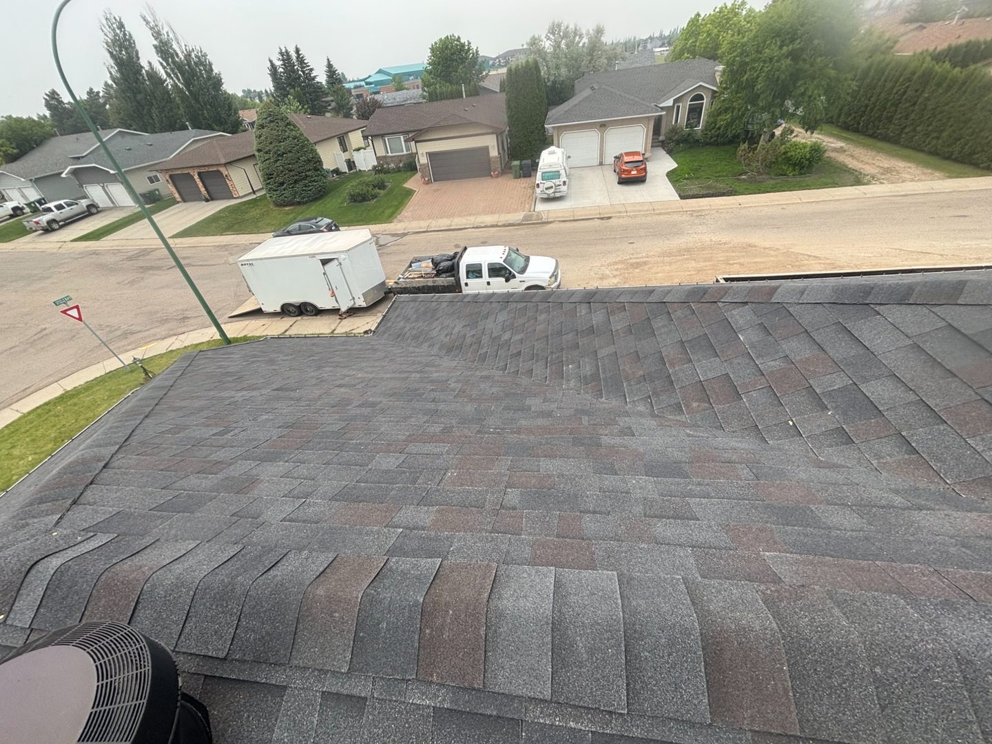 Completed dark shingle roof with Molnar Roofing truck and trailer in Yorkton Saskatchewan neighbourhood