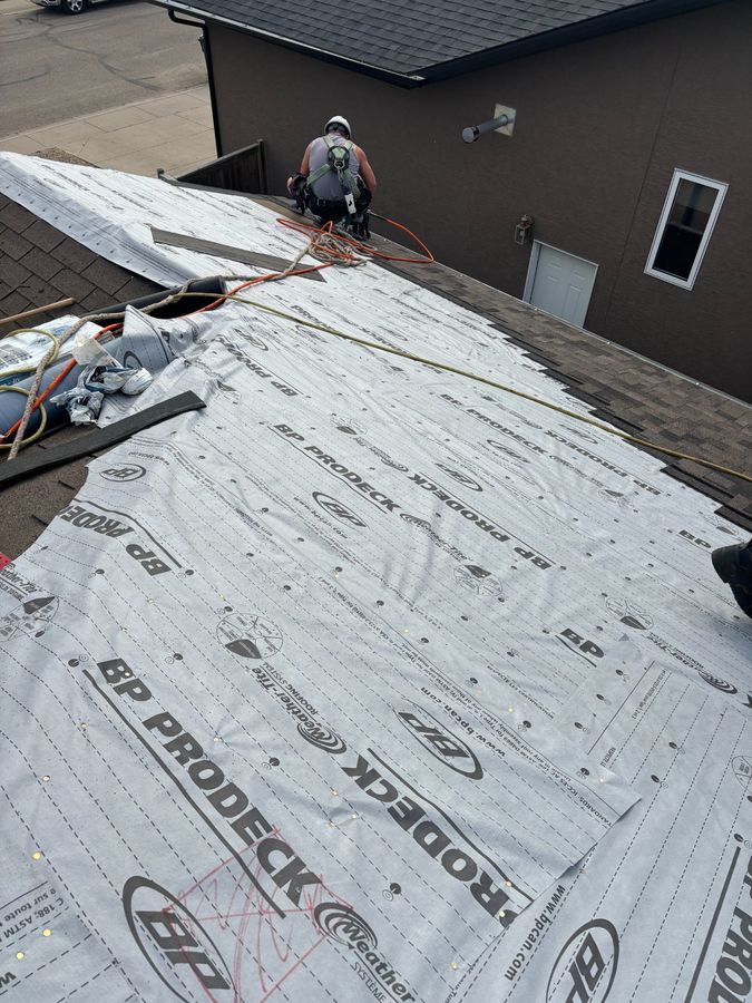 Crew member with safety harness on BP ProDeck underlayment during tear-off