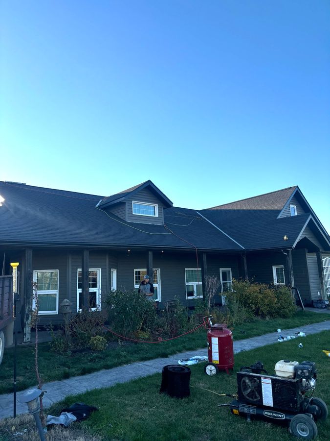 Dark exterior home at dusk with worker on roof