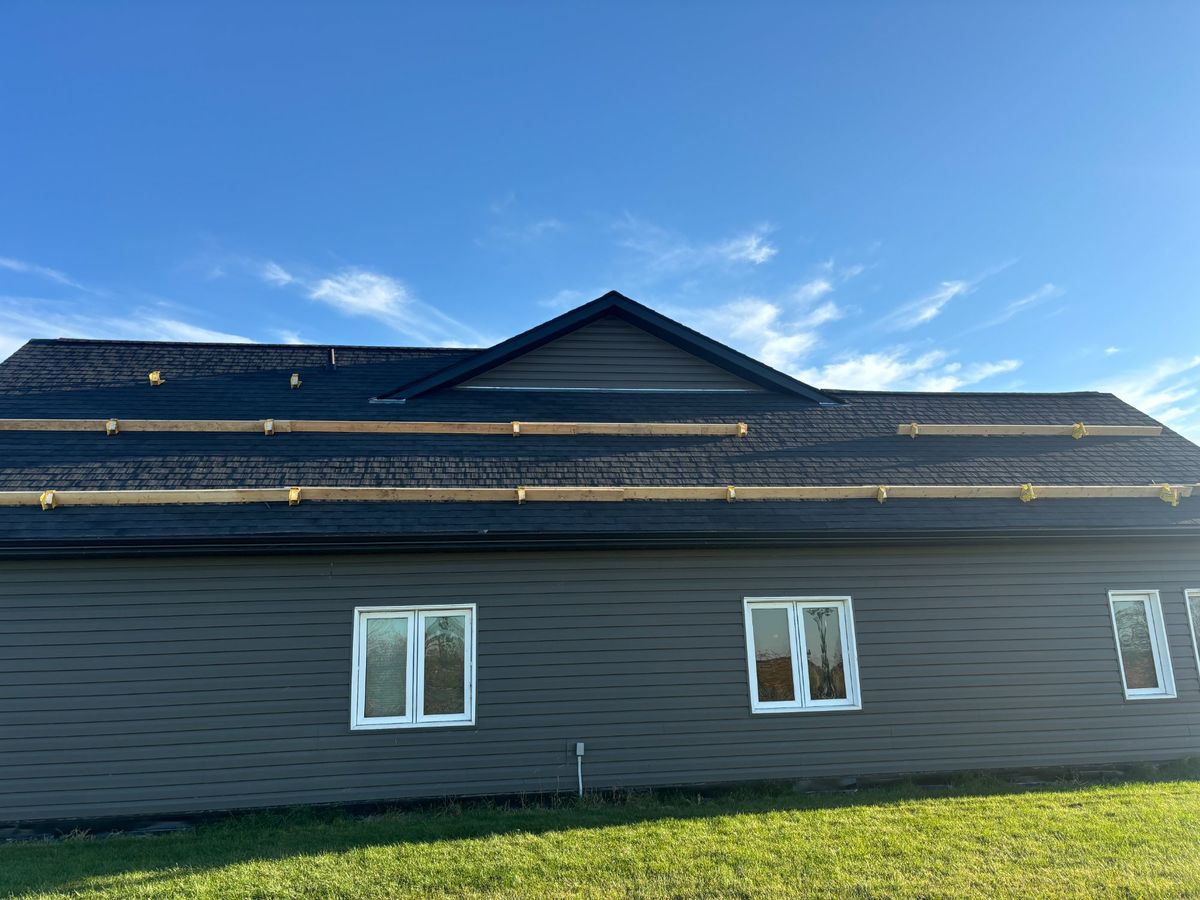 Dark exterior custom home side angle during roof installation