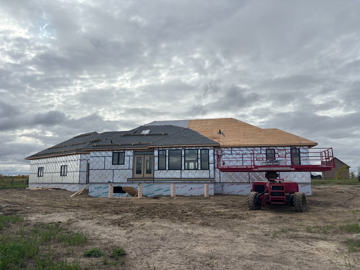 Large new construction home with boom lift during roof installation